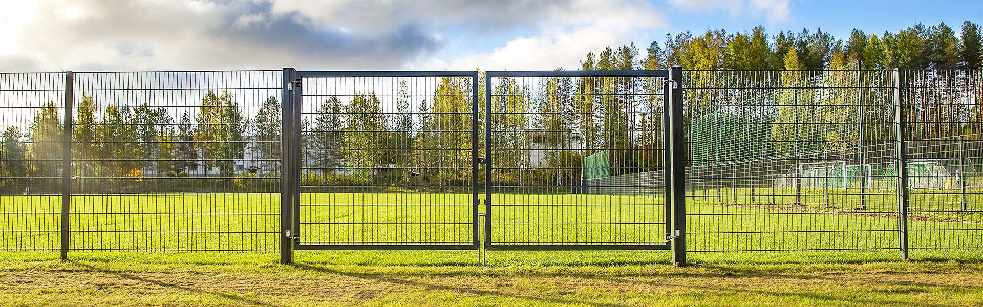 Pallokenttä on ympäröity mustalla elementtiaidalle, jossa on kaksilehtinen saranaportti huoltoajoa varten.