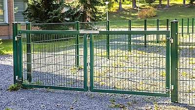 Vihreä elementtiaitaus ympäröi leikkipuistoa ja aitaan on myös yhdistetty kaksilehtinen, saranoitu huoltoportti.
