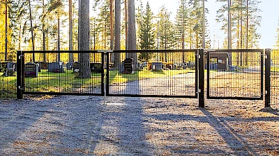 Hautausmaalle johtaa leveä musta elementeistä tehty yhdistelmäportti, jossa on huoltoportti ajoneuvoille ja käyntiportti jalankulkijoille.