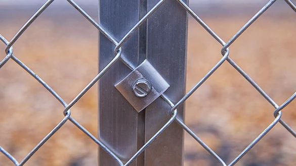 Galvanized chain link fence is fastened to aluminium post with screws and fastening plates.